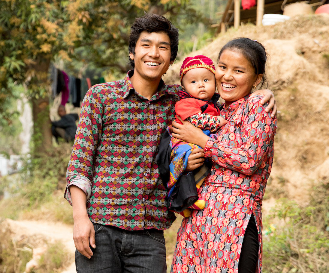 Nepalese mom and dad holding their baby and smiling.